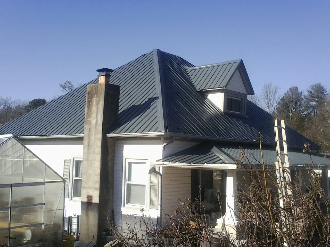 Dark blue standing seam metal roof on a white farmhouse with dormer — Slate & Tile Roof Repair by Roofing Brothers in South Berwick