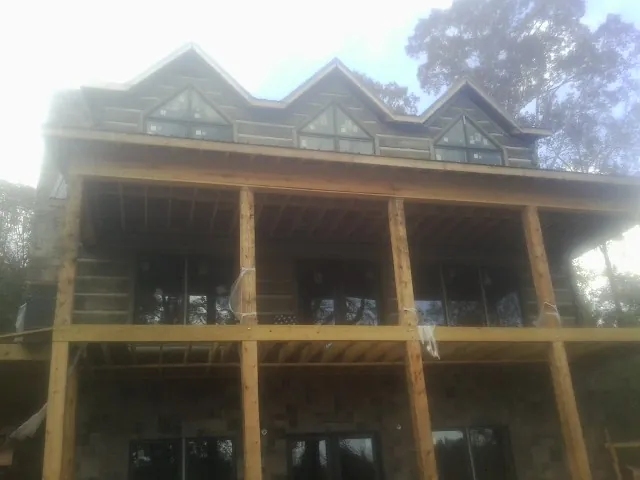 Dormers and porch framing on a large log home under construction — Roof Coating work by our crew in South Berwick