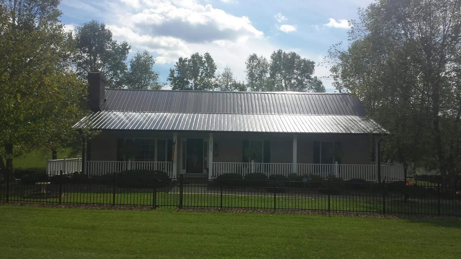 Gray metal roof on a brick ranch with a full width front porch — Gutter Guard Installation work by our crew in South Berwick