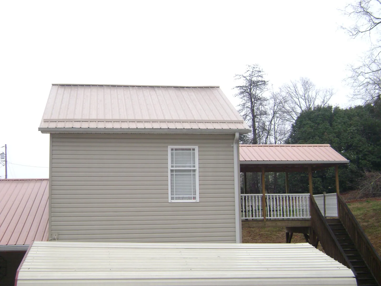 Tan metal roofs on a two story addition and attached porch, from a Roof Replacement job in South Berwick