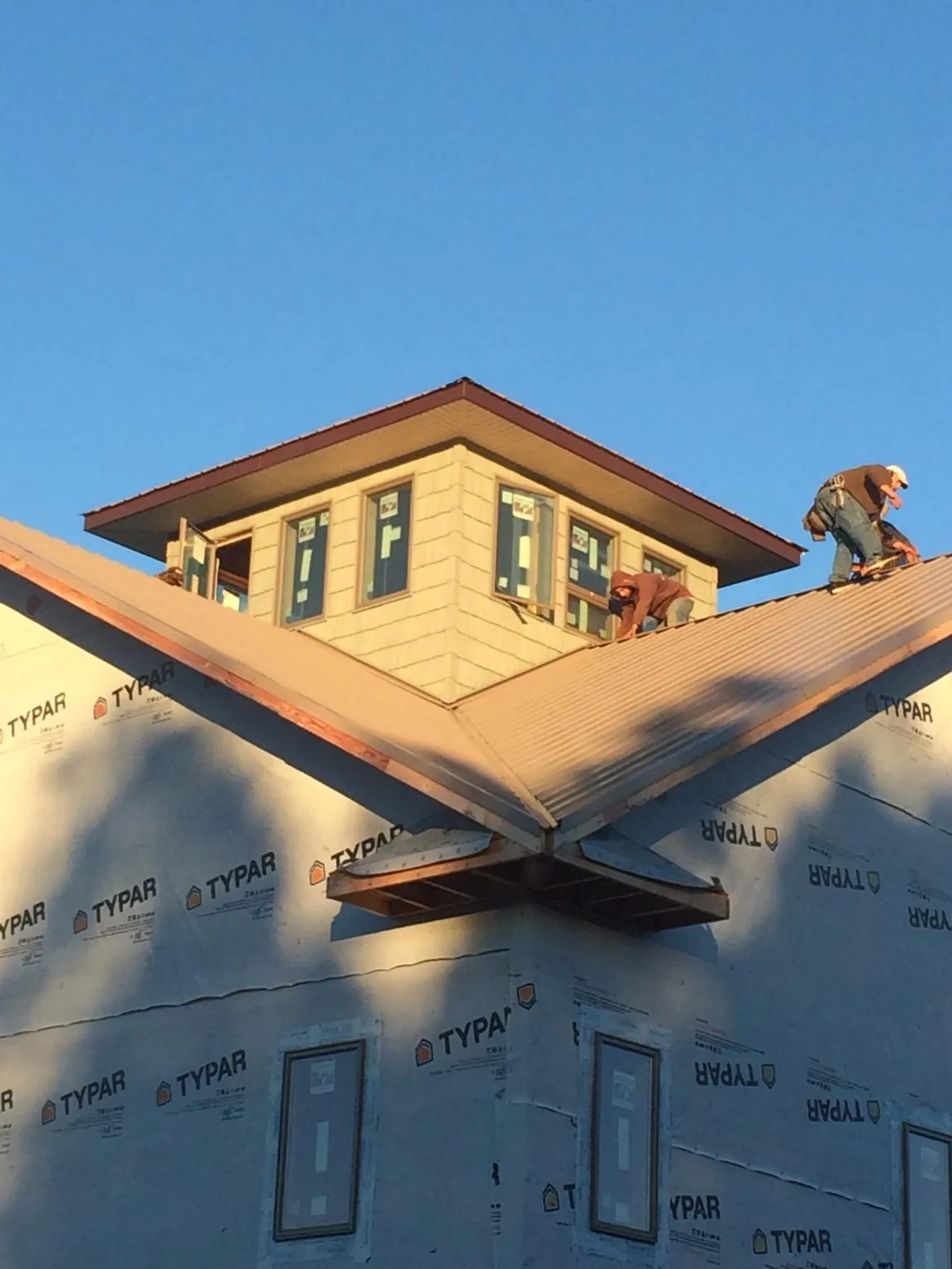 Roofers working around a rooftop cupola on a new metal roof at sunset — Roof Waterproofing in South Berwick by Roofing Brothers